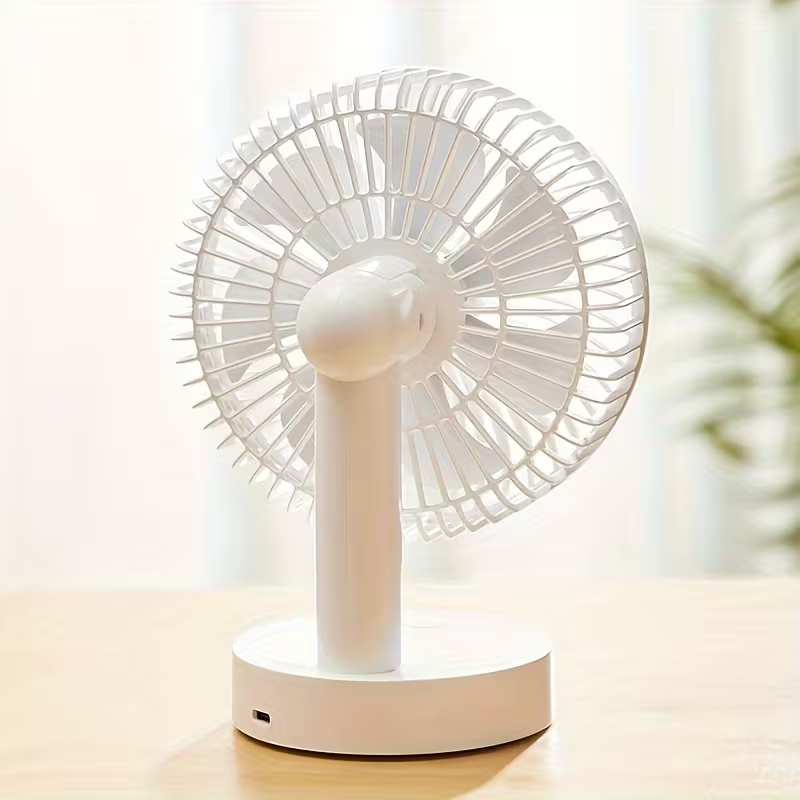 White portable fan on a light surface with a blurred background