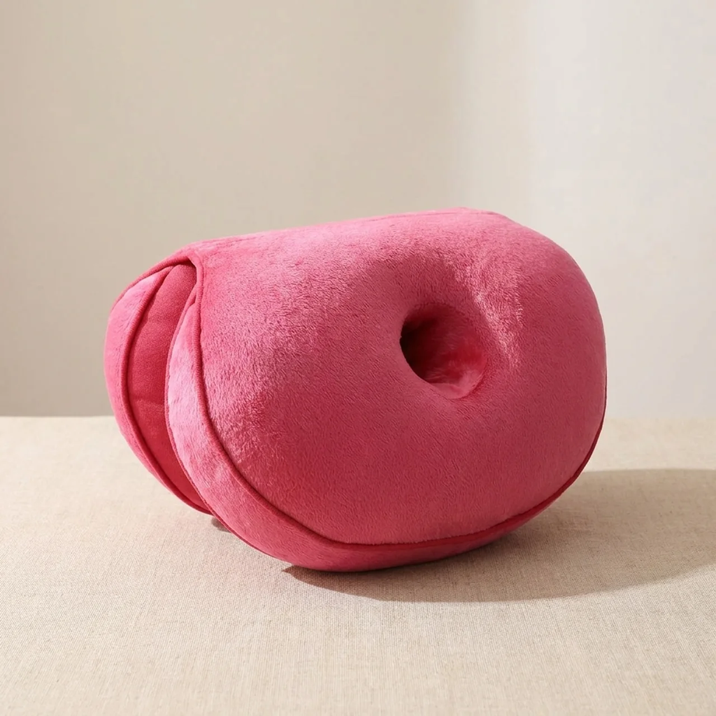 Pink donut-shaped pillow on a beige surface with a neutral background