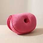 Pink donut-shaped pillow on a beige surface with a neutral background