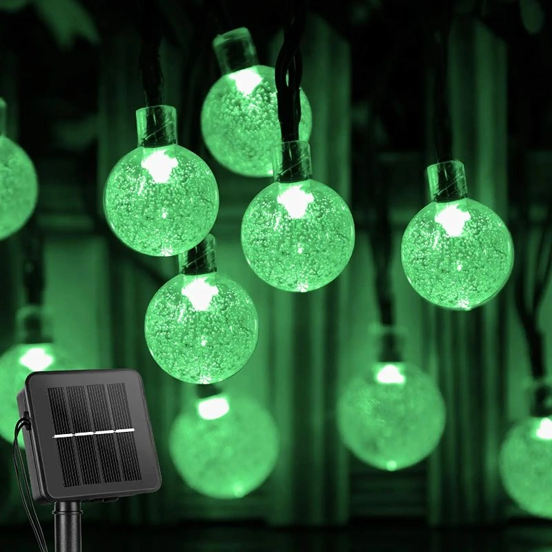 String of green LED lights with a solar panel power source, glowing in the dark.