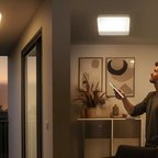 Man using a tablet in a modern living room with a ceiling light fixture.