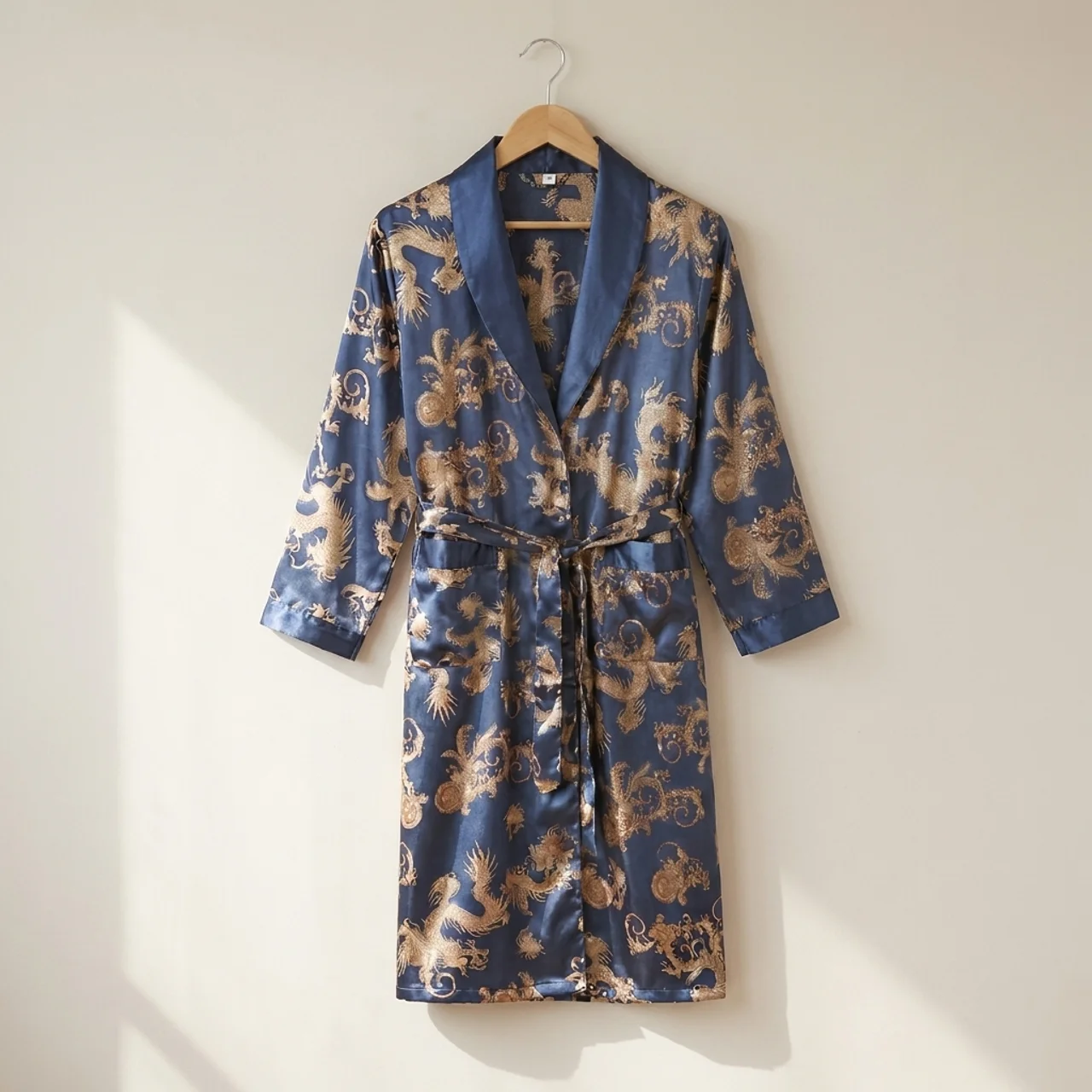 Blue robe with gold dragon pattern on a hanger against a white wall