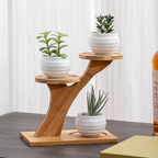 Wooden plant stand with three white pots containing plants on a table.