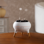 White and gold essential oil diffuser on a wooden surface with steam rising.
