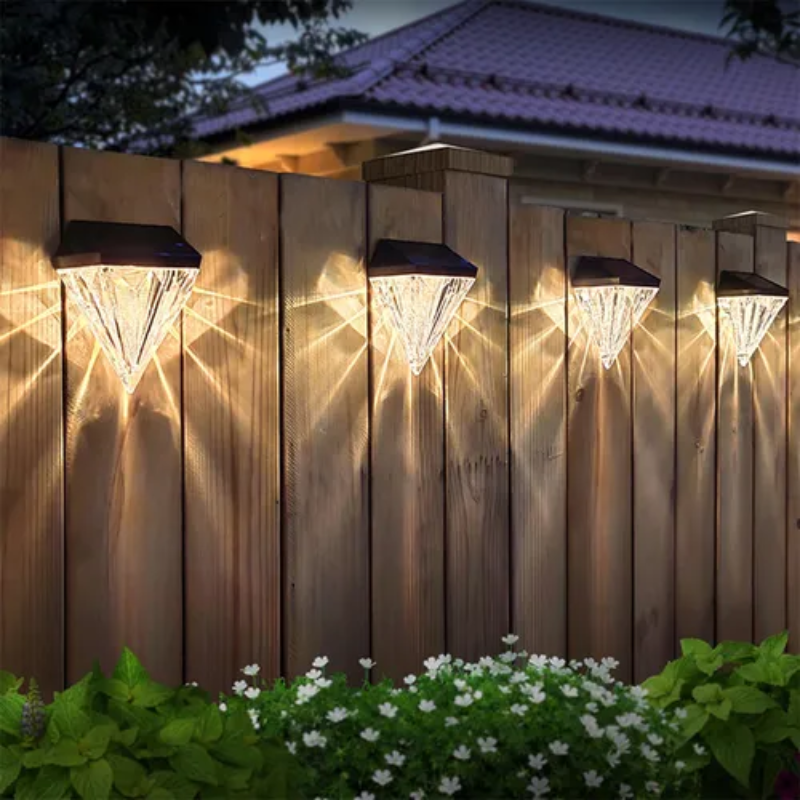 Solar lights on a wooden fence with a house in the background