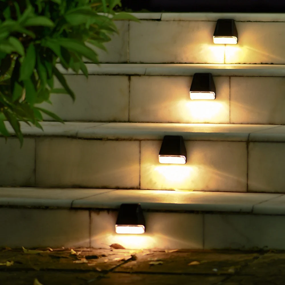 Solar-powered outdoor lights on stone steps with a plant in the corner.