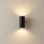 Black cylindrical wall light fixture on a beige wall