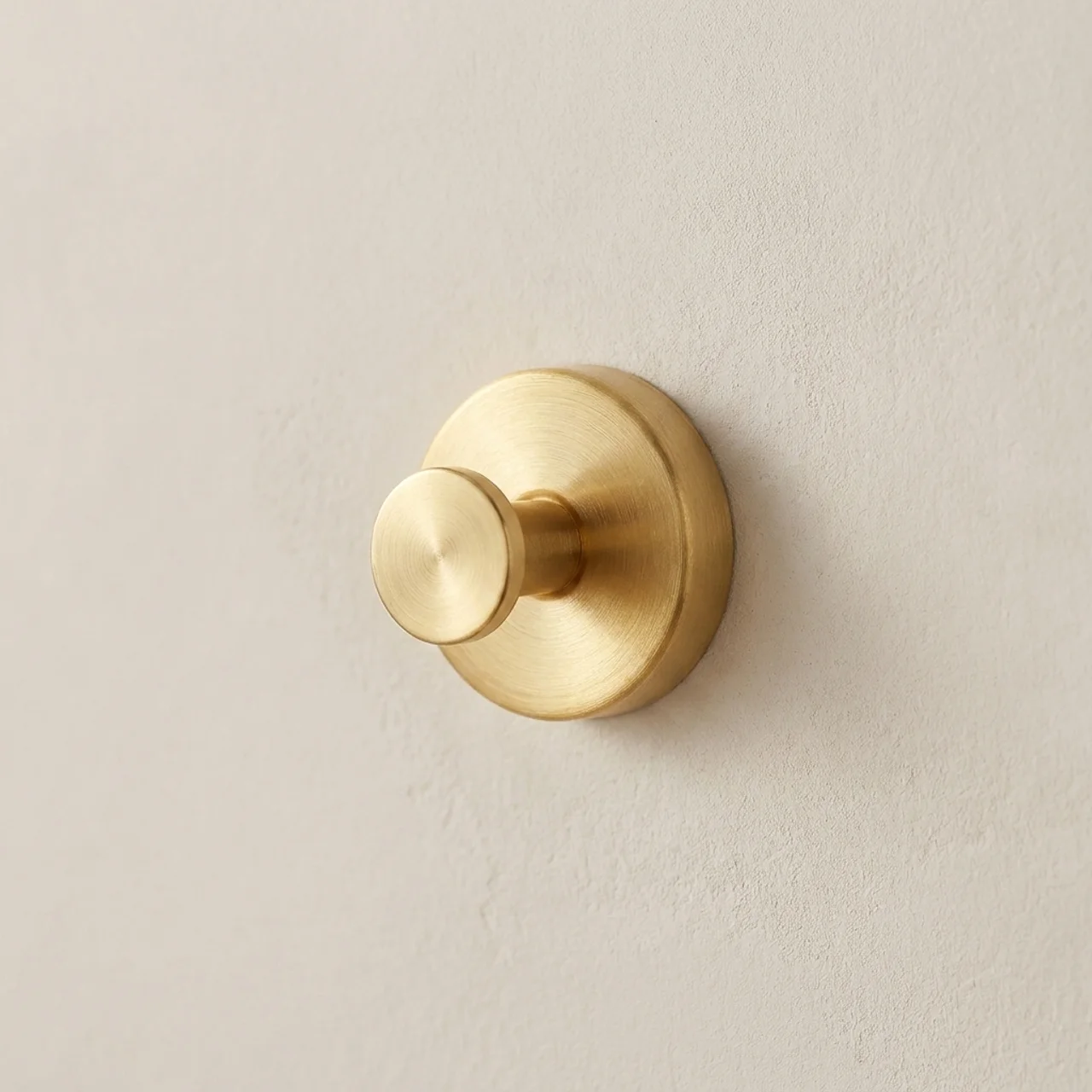 Gold wall hook on a beige wall