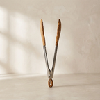 Wooden-handled tongs on a beige background