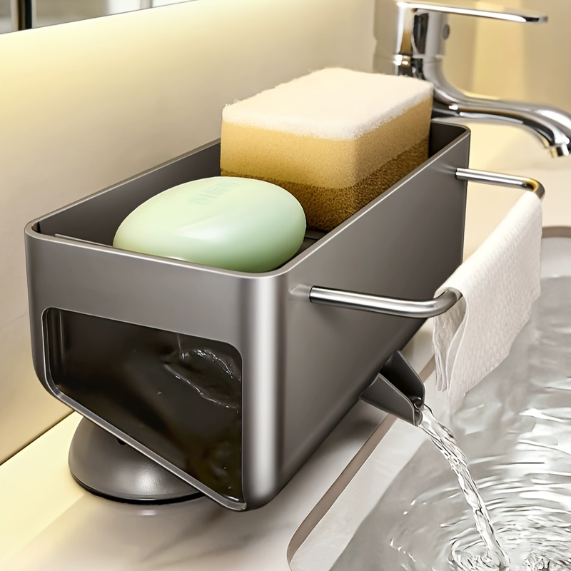 A stainless steel bathroom sink soap dispenser holder with a water-filling feature, shown on a sink with soap bars and a sponge inside.