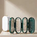 A set of four oval jewelry organizer stands displayed on a beige surface against a warm beige wall. Three stands are open to show interior hanging slots and display cases containing necklaces and earrings, while one stand on the left is closed in white.