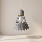 A modern pendant light shaped like a shuttlecock, featuring a matte gray top and bottom, a gold metallic band, and a wire cage holding a clear glass globe bulb, suspended against a minimalist beige background.
