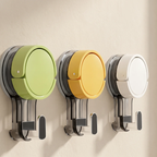 Three wall-mounted hook-and-hold storage holders in light green, mustard yellow, and white, shown against a plain beige wall.
