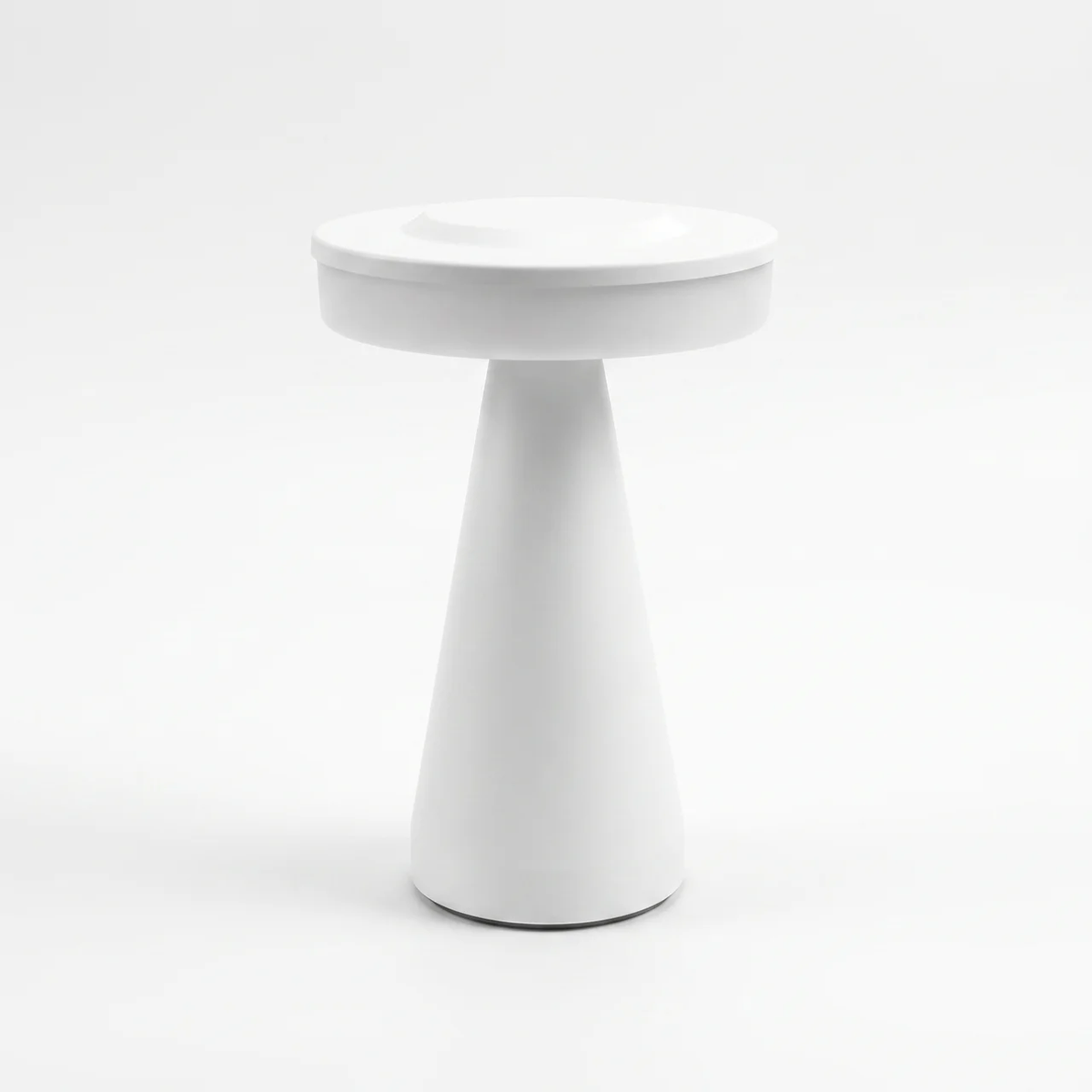 A minimalist white side table with a circular top and a tapered cone-shaped base, photographed on a seamless white background.