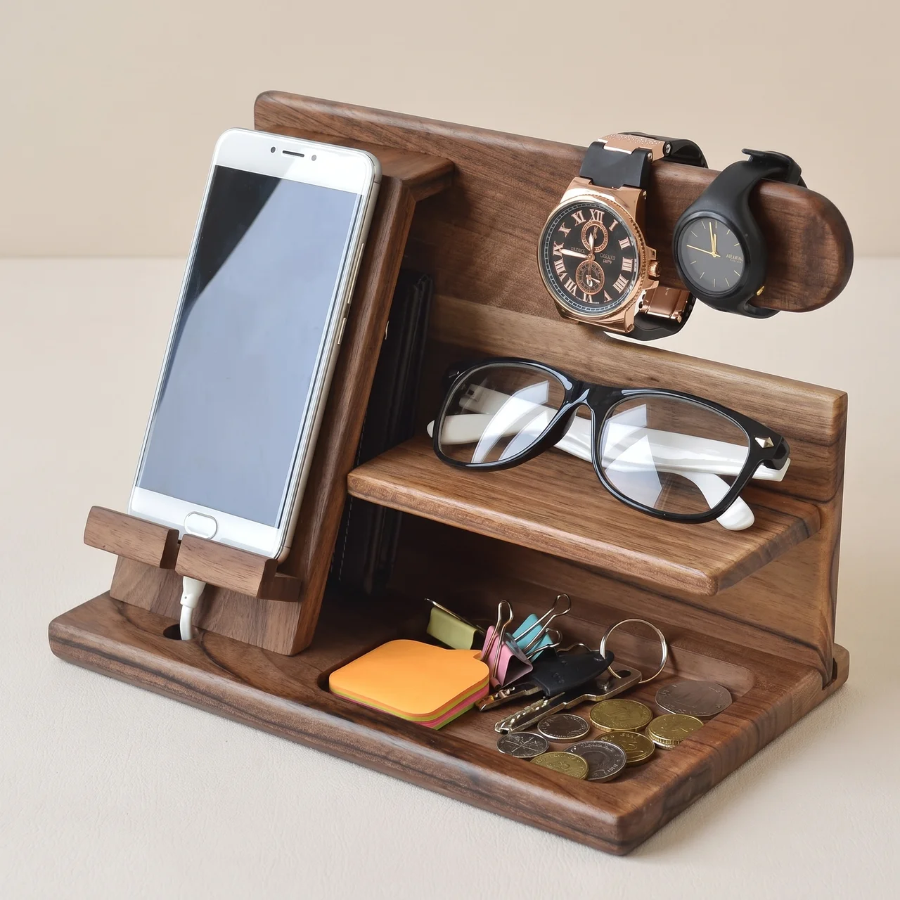 A dark brown wooden desk organizer with multiple compartments, shown holding a smartphone, eyeglasses, two wristwatches, keys, and small accessories on a light beige background.
