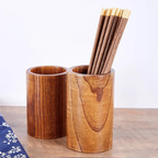Wooden pen holder with two compartments, one holding pens and the other empty, on a wooden surface.