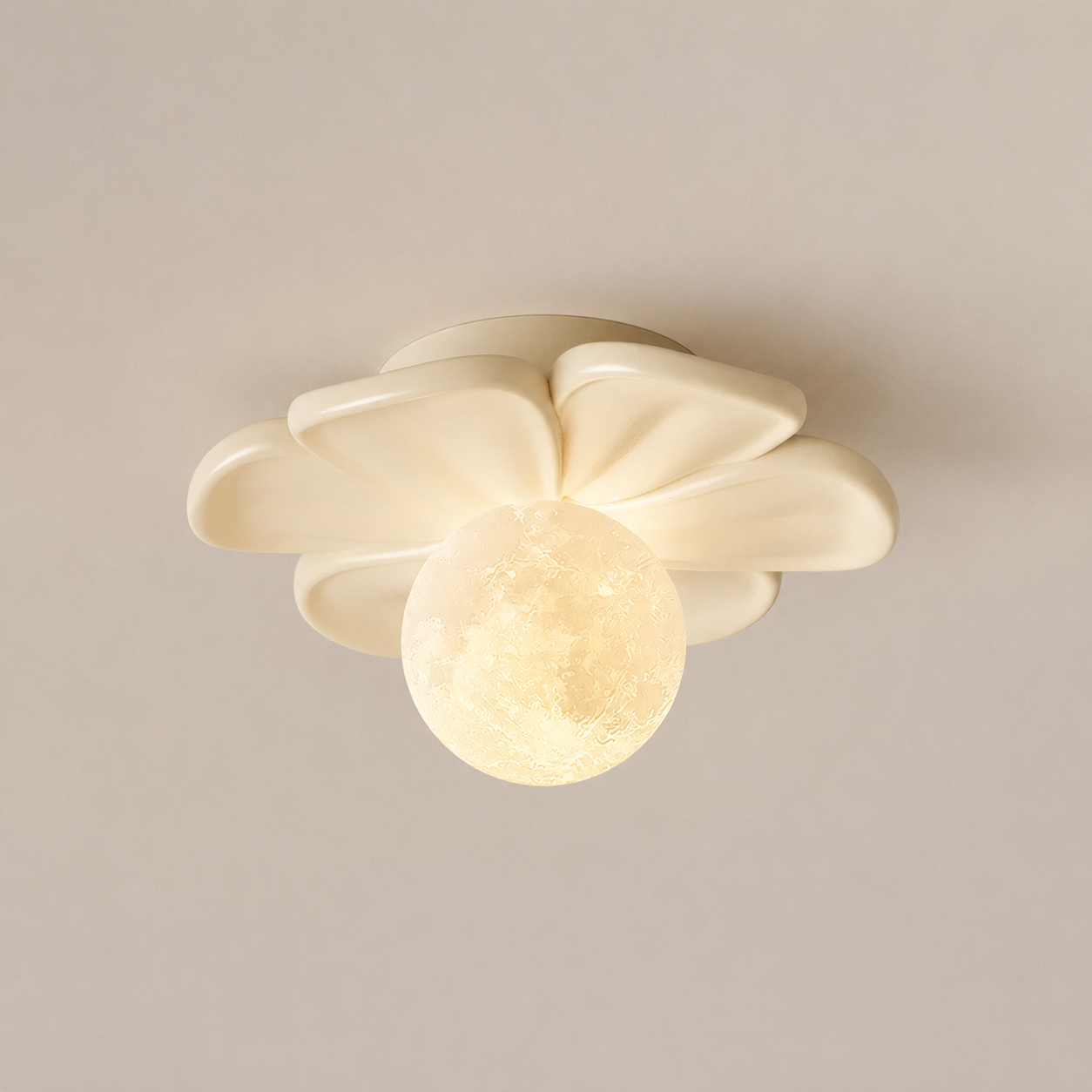 A modern ceiling light fixture with a flower-like cream shade and a glowing spherical moon-shaped bulb, shown against a plain beige wall.