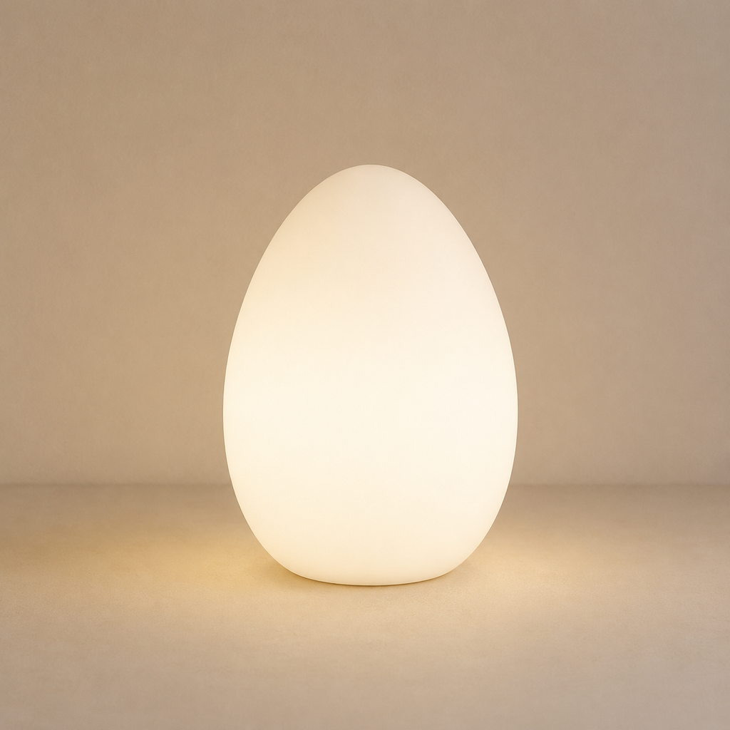 A glowing egg-shaped table lamp with a smooth matte finish, emitting a warm white light against a neutral beige background.