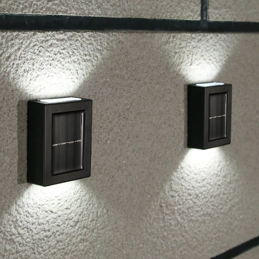 Two black rectangular solar wall lights mounted on a textured beige stucco wall, casting bright downward light beams.