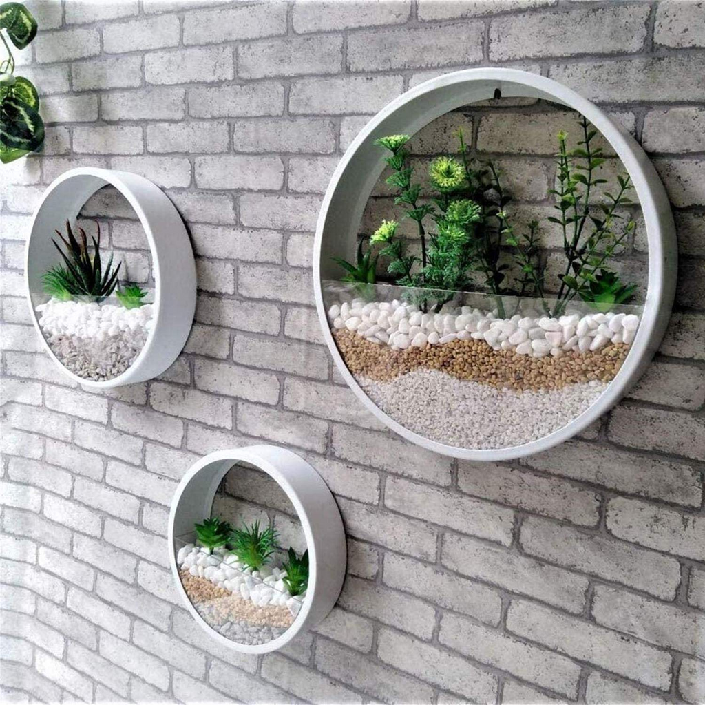 Three round white wall-mounted planters with faux succulents and gravel, mounted on a gray brick wall.