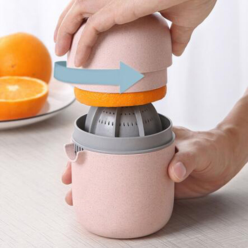 Pink manual juicer with orange being squeezed on a light surface.