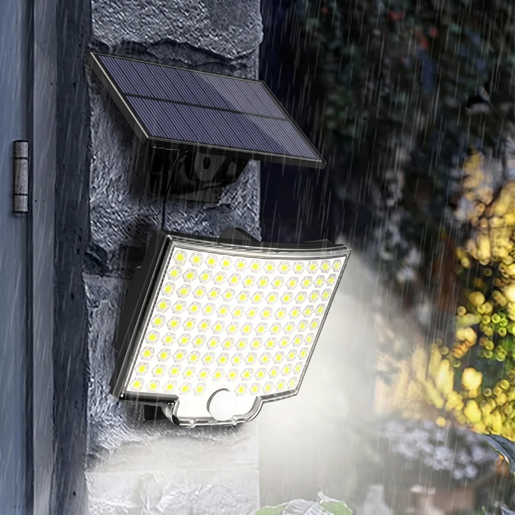 Solar-powered outdoor wall light with an integrated solar panel and bright LED light bar, mounted on a stone wall in the rain.