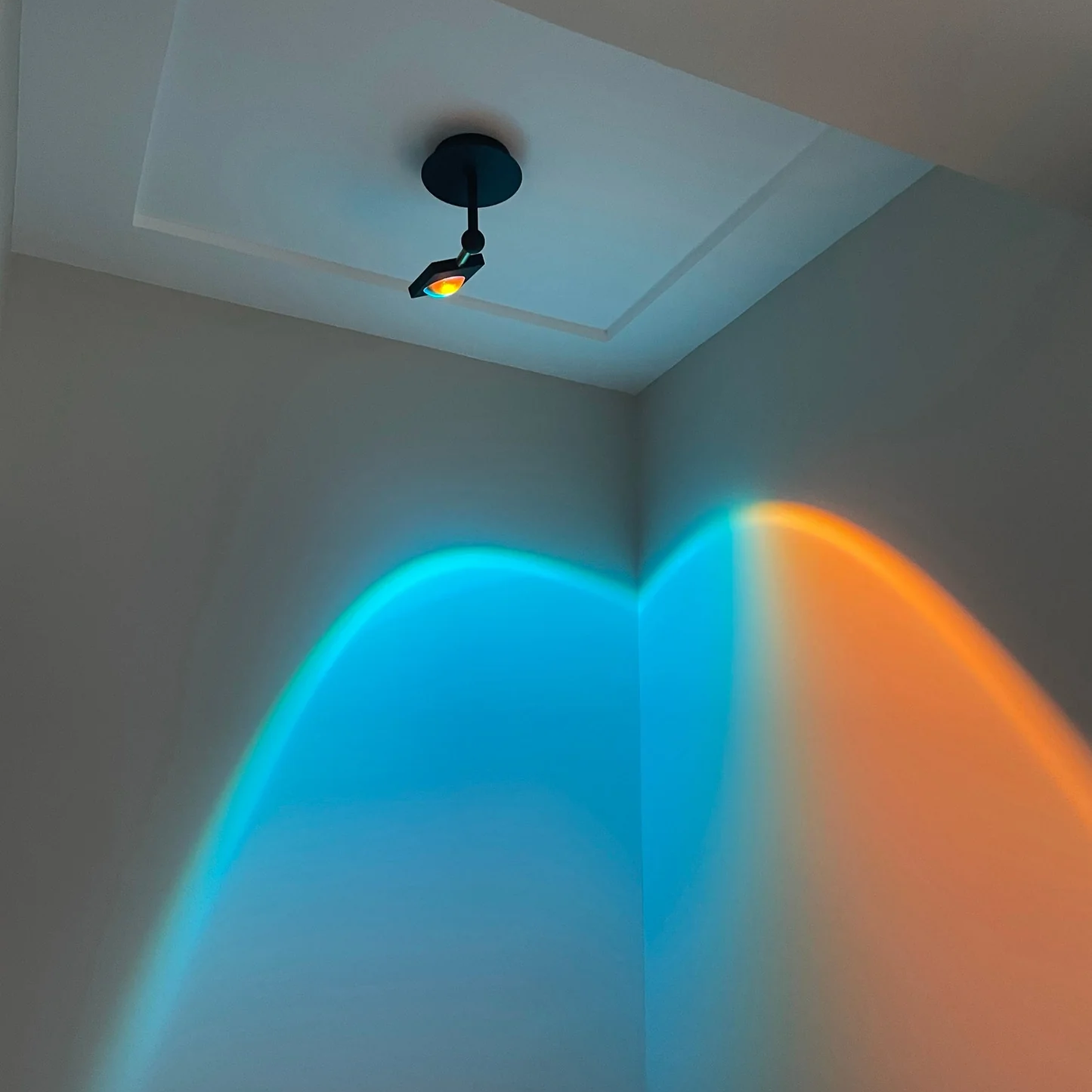 Light fixture casting blue and orange beams on a wall