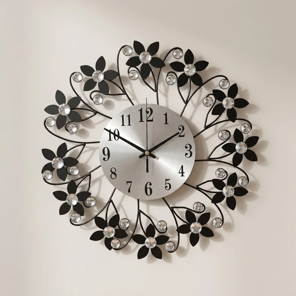 A decorative wall clock with a silver round face and black metal floral branches surrounding it, accented with clear rhinestones on a plain light background.