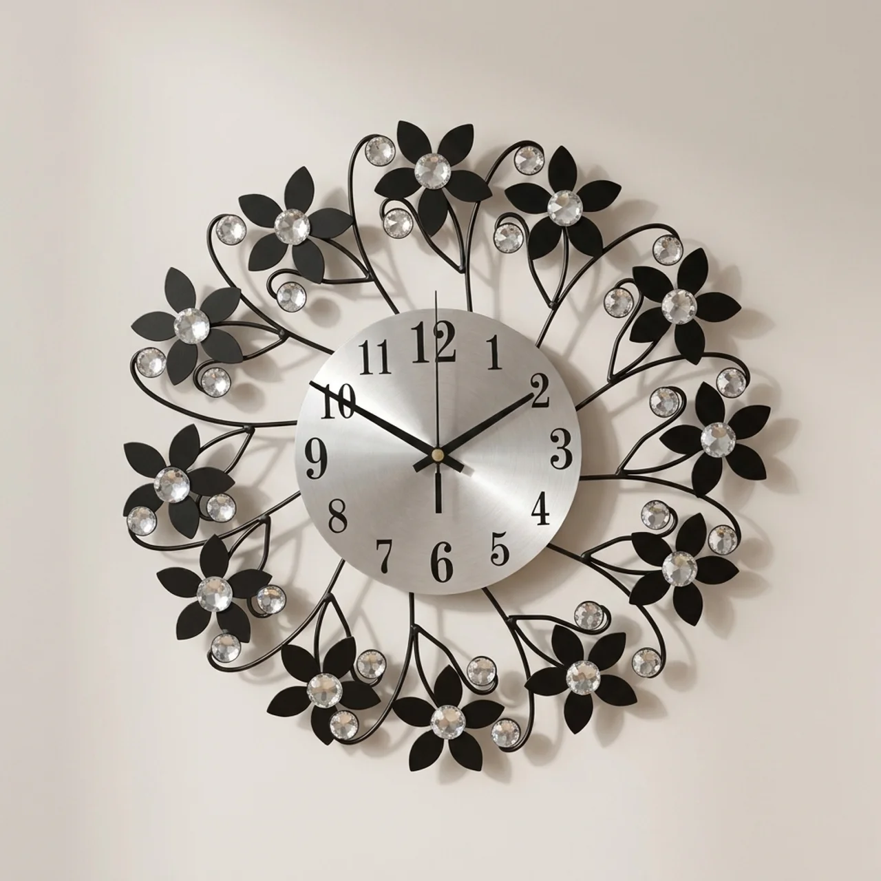A decorative wall clock with a silver round face and black metal floral branches surrounding it, accented with clear rhinestones on a plain light background.