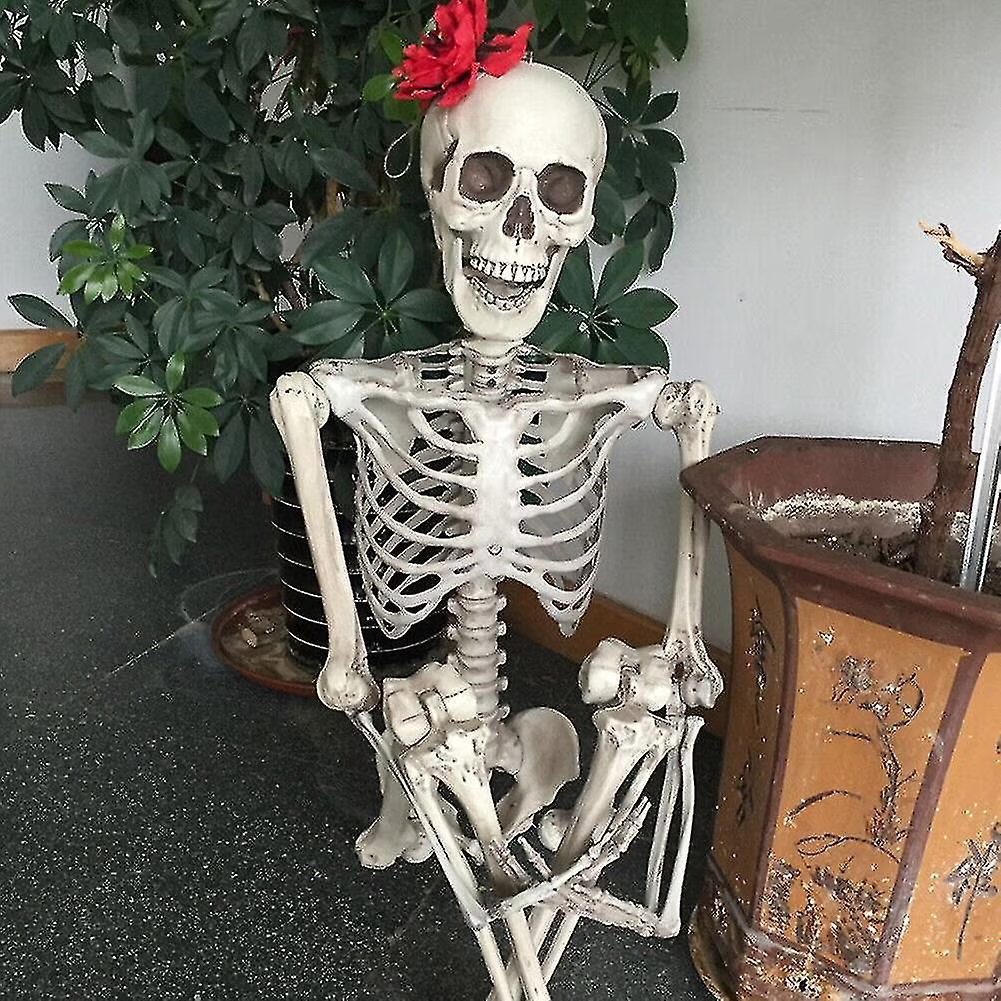 Skeletal figure with a red flower on its head sitting next to a wooden chest.
