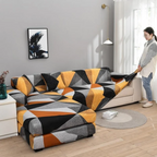 A woman in a home setting adjusts a geometric-patterned sofa slipcover on a sectional sofa. The cover features a modern abstract design in orange, yellow, black, gray, and white.