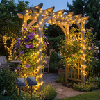 Warm white solar-powered garden string lights draped over a wooden garden archway, illuminating climbing flowers and a stone garden path at dusk.