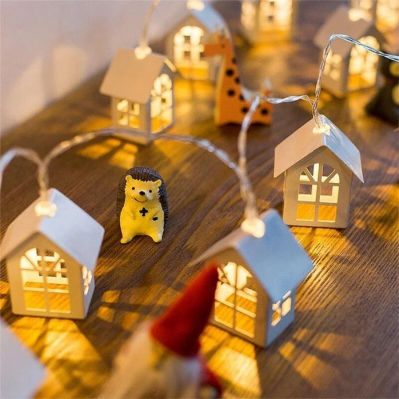 Decorative setup with small houses and a hedgehog figurine on a wooden surface.