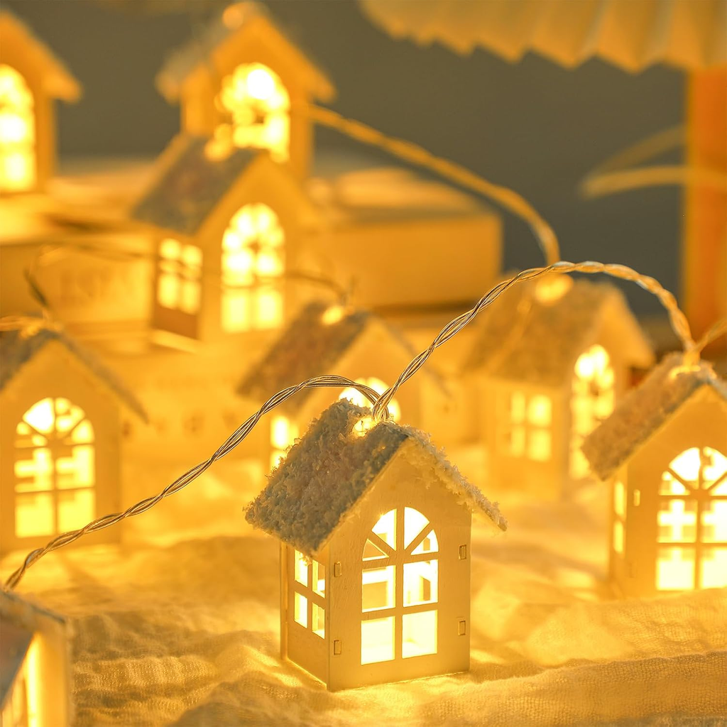 Warm white LED house string lights with snow-dusted roofs, glowing with a cozy golden-yellow light in a festive setting.
