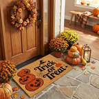 A coir doormat with 'Trick or Treat' text and jack-o'-lantern graphics is displayed in a festive, decorated entryway with pumpkins, mums, and a wooden door.