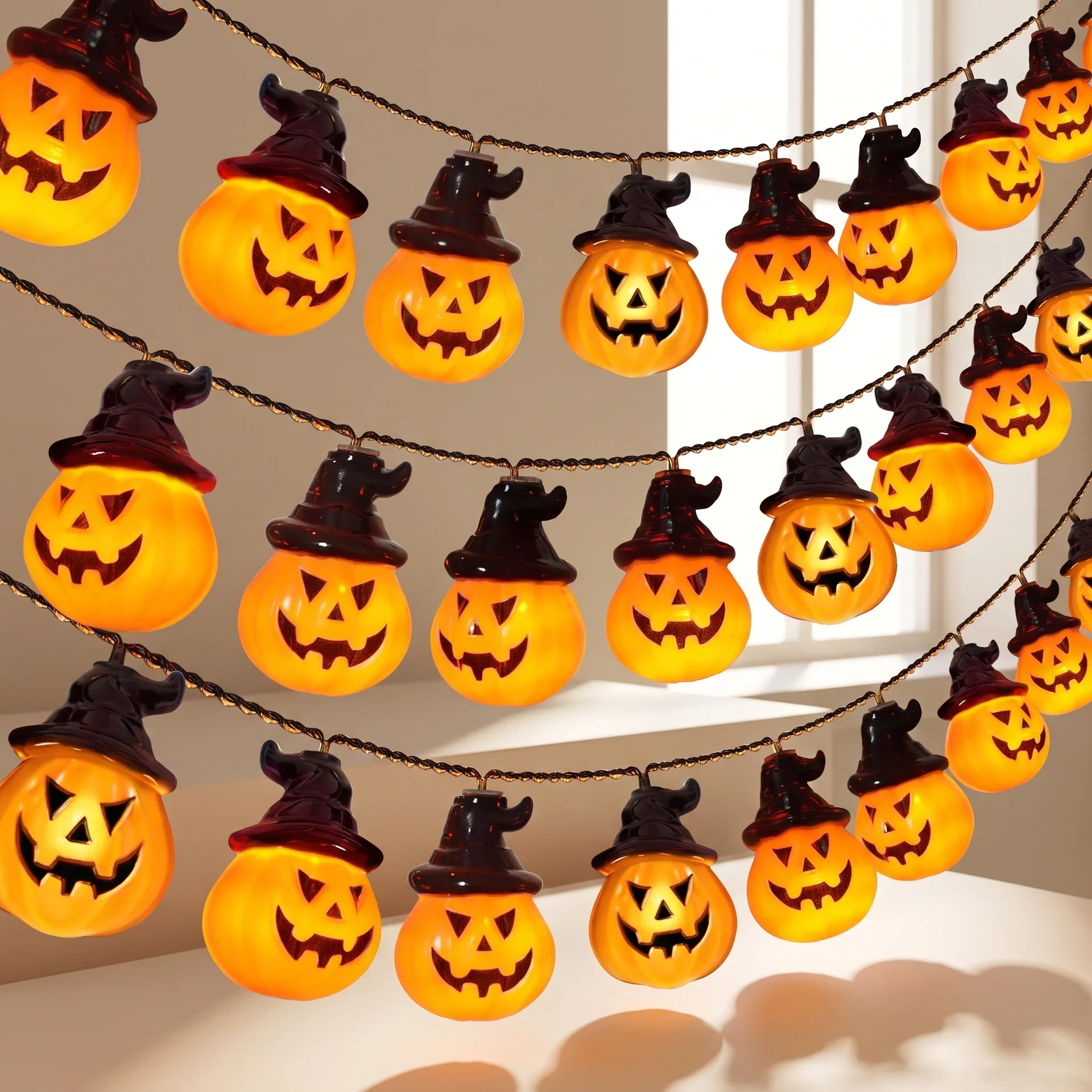 Halloween string light garland featuring glowing orange jack-o'-lantern bulbs shaped like witch hats, hanging in three rows against a softly lit indoor background.