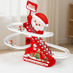 A festive Christmas-themed toy track set featuring a red staircase tower, white spiral tracks, small rolling Santa figures, and a Santa-decorated base, photographed indoors on a tabletop with a softly blurred room background.