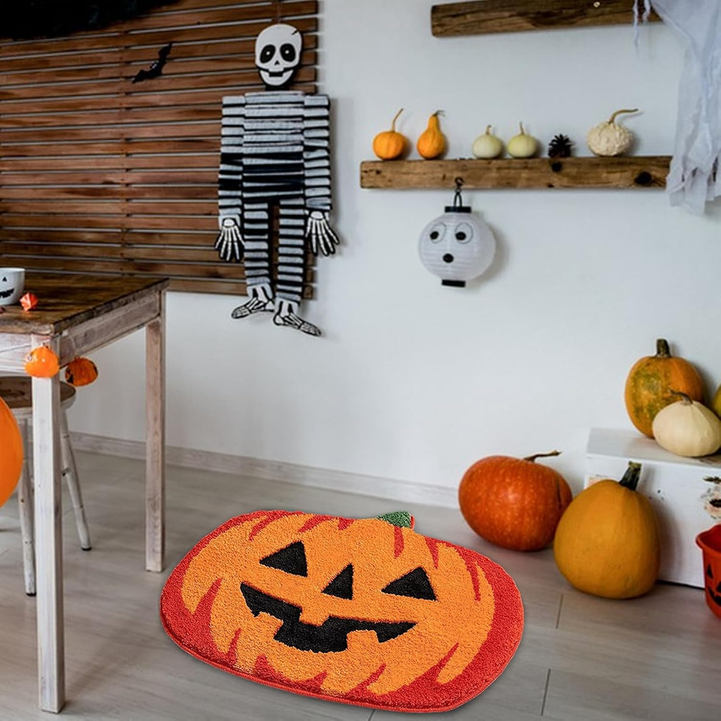 A Halloween-themed room decorated with pumpkins, a skeleton cutout, and seasonal wall decor. The main product shown is an orange and red pumpkin-shaped rug with a jack-o'-lantern face on the floor.