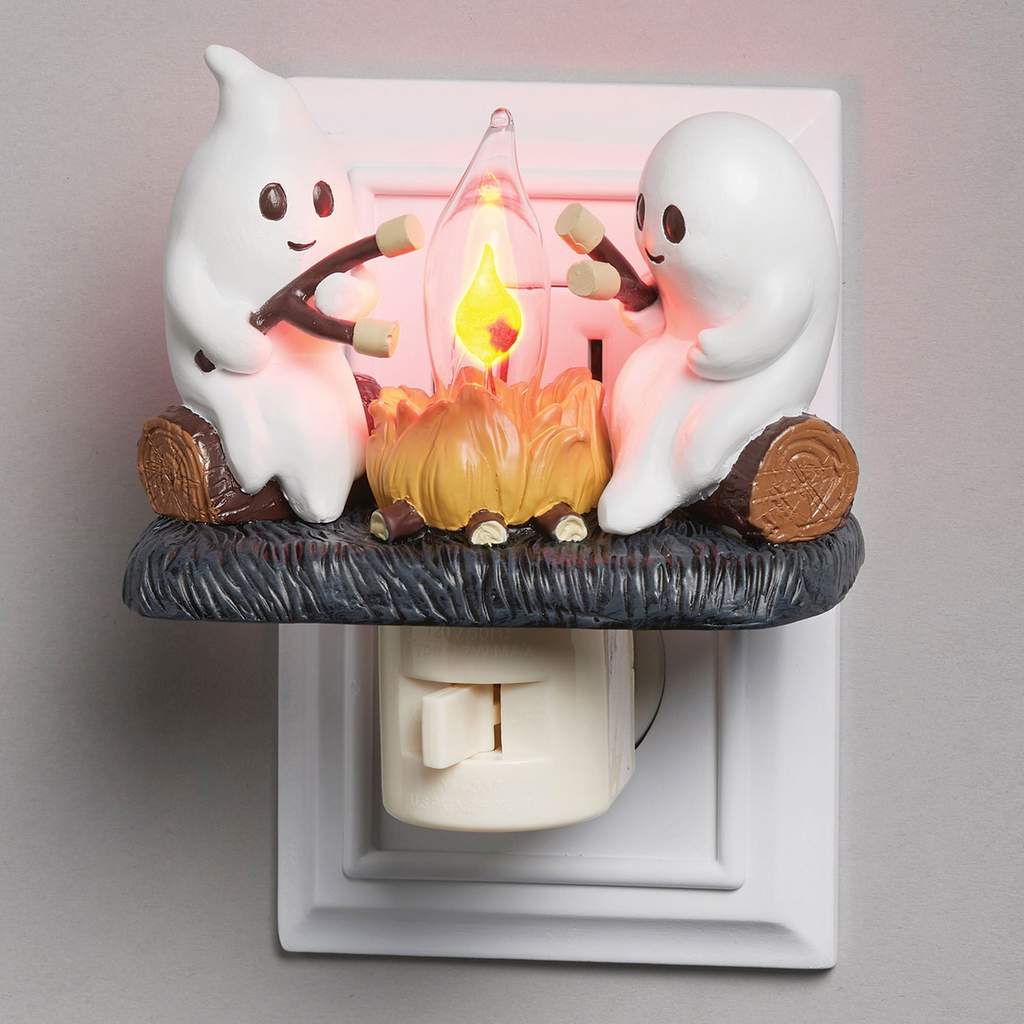 Decorative night light with ghost characters around a campfire on a neutral background