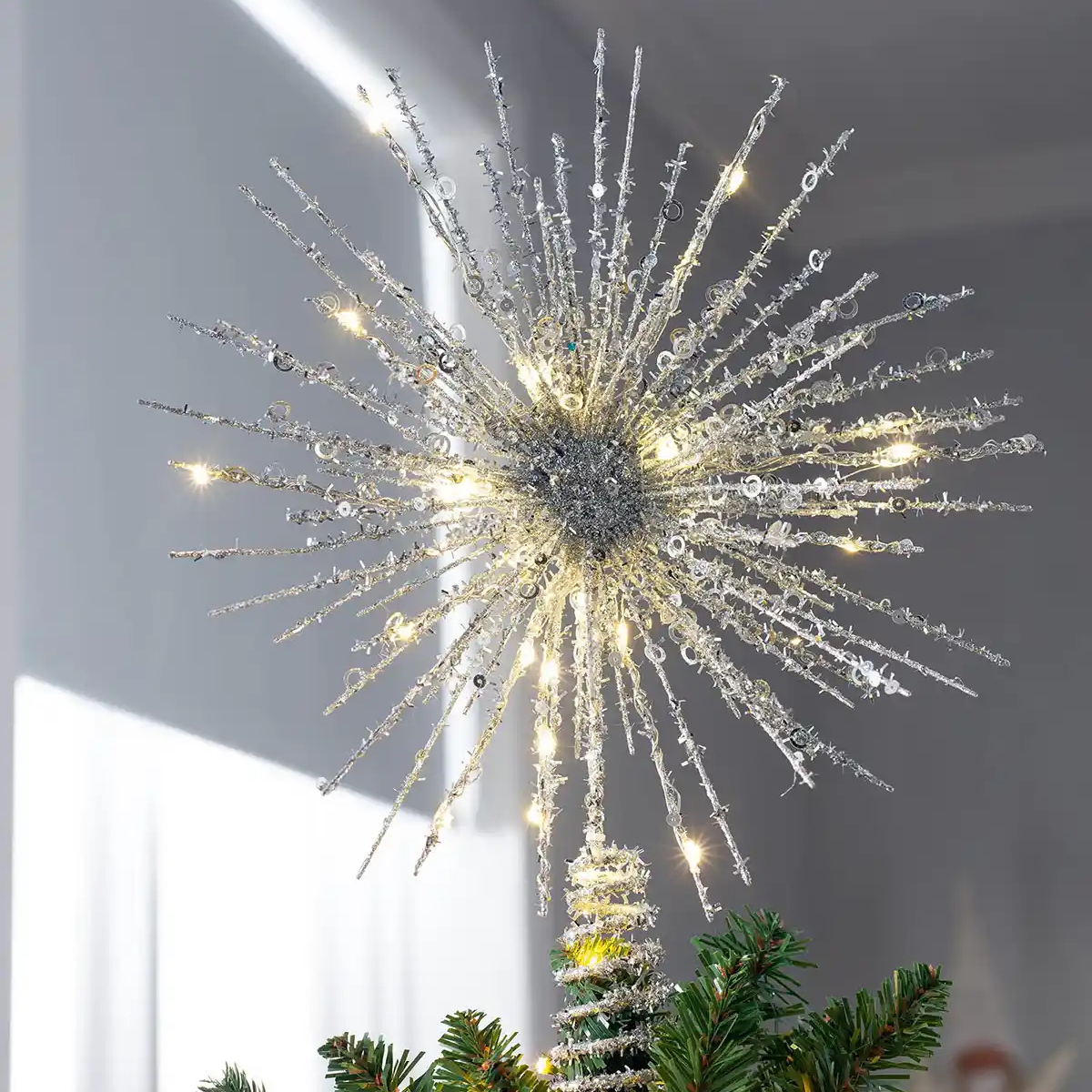 Decorative Christmas tree topper with starburst design on a Christmas tree.