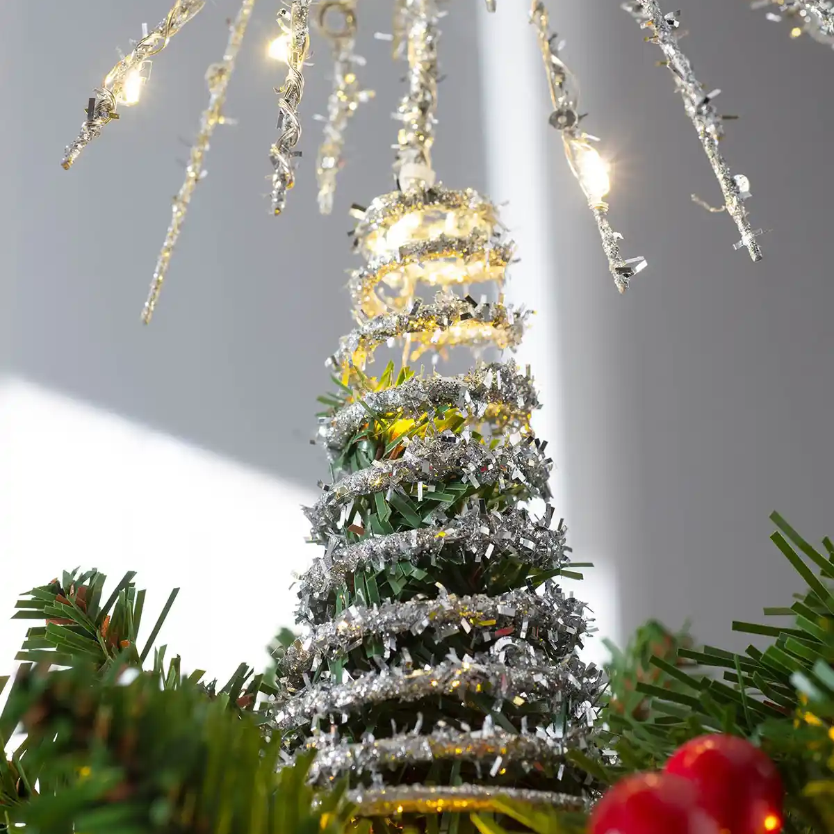 Decorative Christmas tree with lights and red berries on a gray background