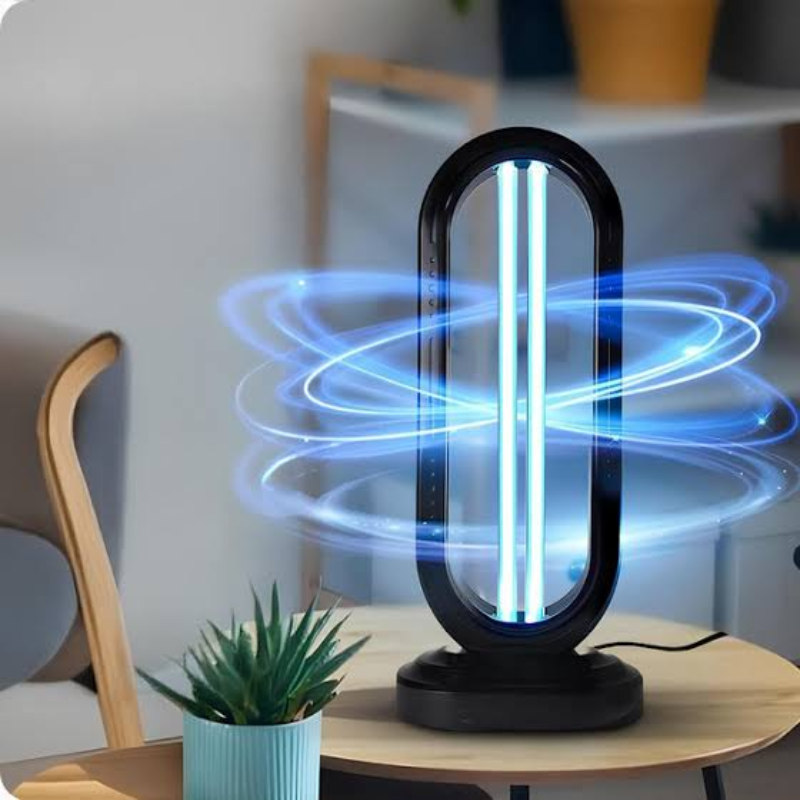 A black UV light lamp with glowing blue light rings, shown on a wooden table in a modern room setting.