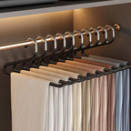 A black multi-hanger rod system holding multiple hangers with folded garments in a closet setting, with warm ambient lighting and a metallic rod visible.