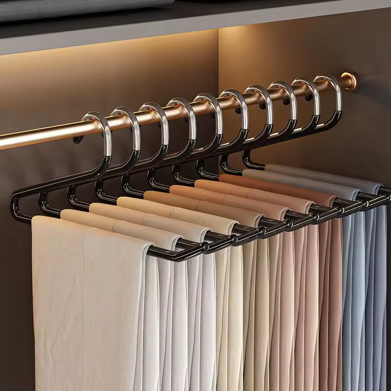 A black multi-hanger rod system holding multiple hangers with folded garments in a closet setting, with warm ambient lighting and a metallic rod visible.