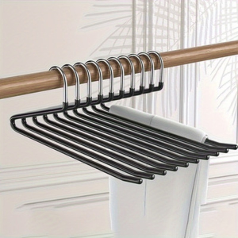 A set of black multi-hanger clothes hangers with silver metal hooks, shown hanging from a wooden rod on a light-colored wall.