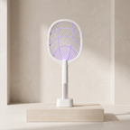 A white electric fly swatter with a glowing purple UV light grid, standing on a light wood pedestal against a minimalist beige wall.