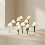 A set of small mushroom-shaped table lamps with glowing warm white caps and dark green stems, arranged on a textured beige surface against a neutral cream background.