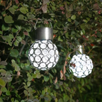 Solar-powered decorative lights hanging among green leaves