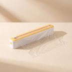 A clear plastic wrap sealer tool with a white body and yellow top, shown sealing clear plastic wrap on a beige surface with soft shadows.