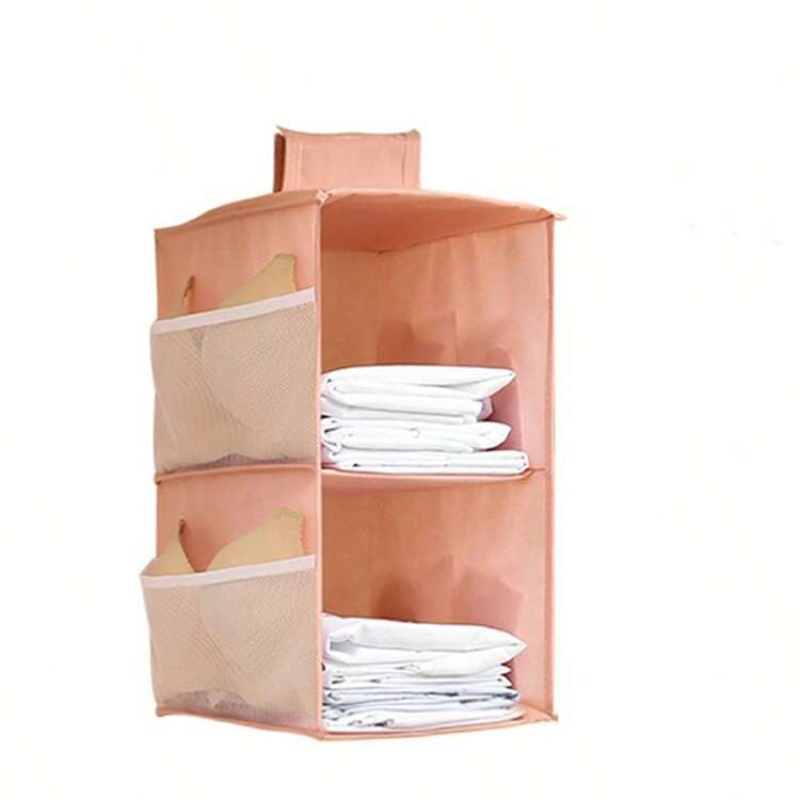 A peach-colored fabric hanging organizer with mesh side pockets and two open shelves, shown holding folded white towels or sheets against a plain white background.